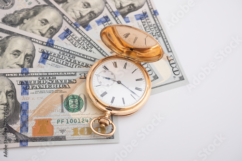 Macro shot of pocket watch face with 100 dollar bill Ben Franklin money and time concept - old pocket watch on pile of american bill dollars