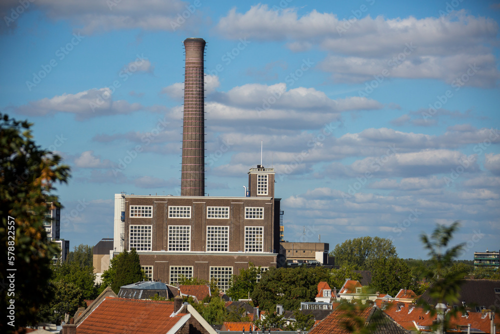 old factory building with high chimney industrial windows blue sky with clouds