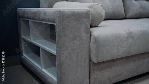White, square shelves inserted at the edge of a comfortable beige sofa. Beige decorative pillows. 4k video.