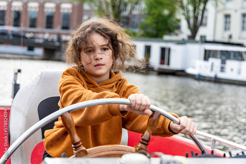A girl at the wheel of a boat on a canal in Amsterdam