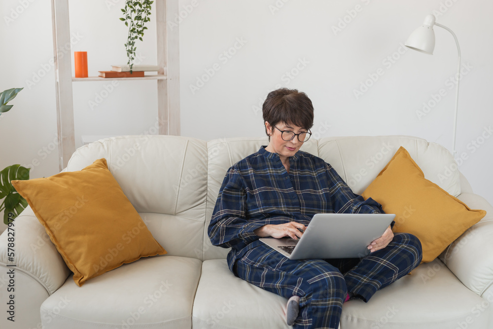 Businesswoman working on laptop computer sitting at home in pajama home wears and managing her business via home office during Coronavirus or Covid-19 quarantine Businesswoman working on laptop computer sitting at home in pajama home wears and managing her business via home office during Coronavirus or Covid-19 quarantine