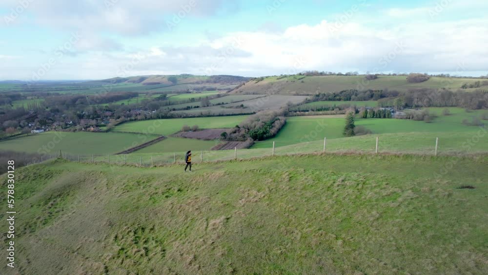 backpack hiking man walking upward to hill, winter in Pewsey, Wiltshire, England backpack hiking man walking upward to hill, winter in Pewsey, Wiltshire, England