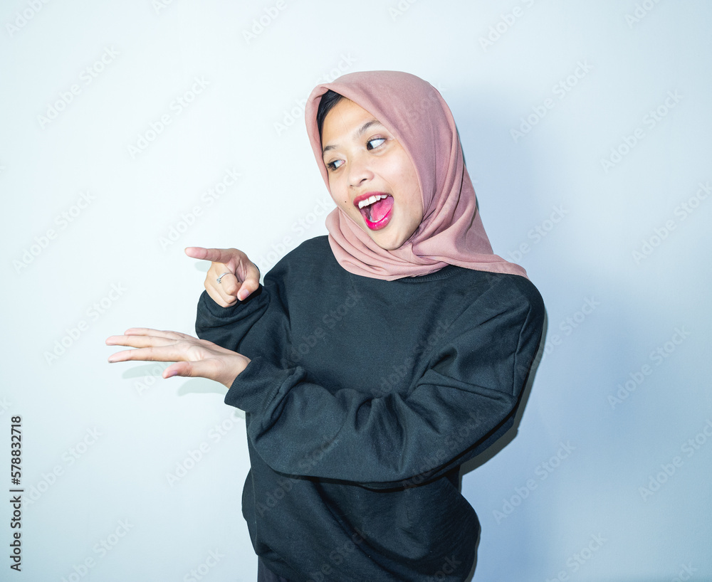Beautiful asian hijab woman with hands pointing empty space presenting with smiling and confidently Beautiful asian hijab woman with hands pointing empty space presenting with smiling and confidently