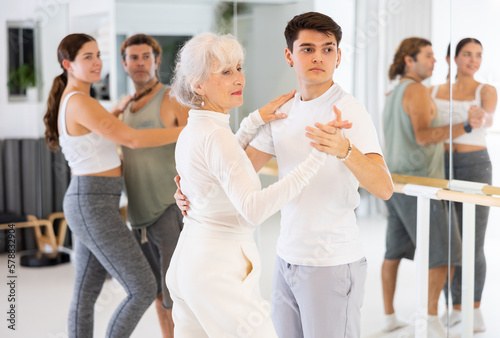 Active sportive men and women enjoying of partner dance in the dance studio