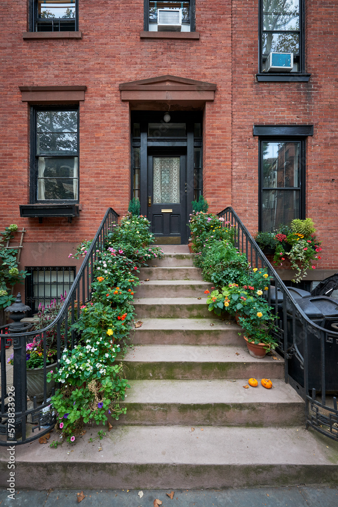 a brownstone building with a lot of blooming flowers on an iconic street in Manhattan, New York City - obrazy, fototapety, plakaty 