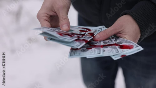Counting blood, Dirty money, Criminal wealth. The hands of a man are tallying up money stained with blood. photo