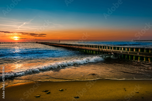 Fototapeta Naklejka Na Ścianę i Meble -  sunset over the sea, beach, sea, wooden breakwater, colorful background, wallpaper for projects, holiday landscape