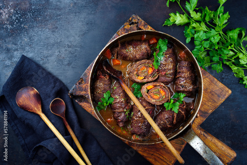 Traditional slow cooked German wagyu beef roulades with vegetable and bacon served in spicy gravy sauce as top view in a copper casserole