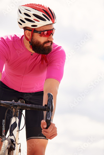 Portrait of a professional cyclist in sportswear, a protective helmet and goggles in a pink jersey against the blue sky, copies. The concept of an active and healthy lifestyle.