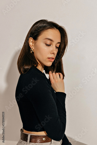 Close up portrait of tender beautiful woman with short dark hairstyle is looking down, closed eyes and touching her chin over isolated background