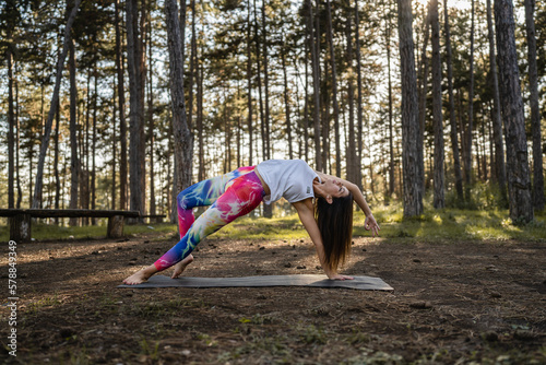 One caucasian woman practice yoga in the nature in woods or park alone healthy lifestyle meditation and modern relaxation antistress stretching concept copy space front view full length