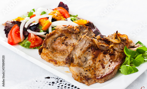 Delicious fried pork loin served with healthy summer salad of fresh vegetables ..