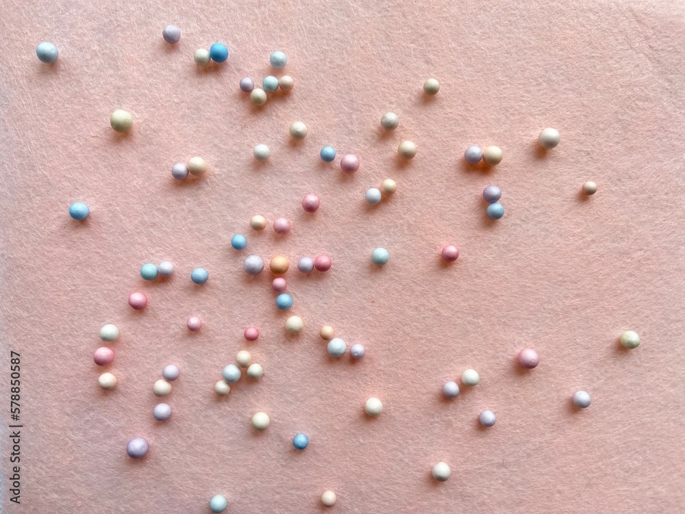 Pink background with colored beads. Texture and delicate background for cosmetics and text. Pink background with colored beads. Texture and delicate background for cosmetics and text.