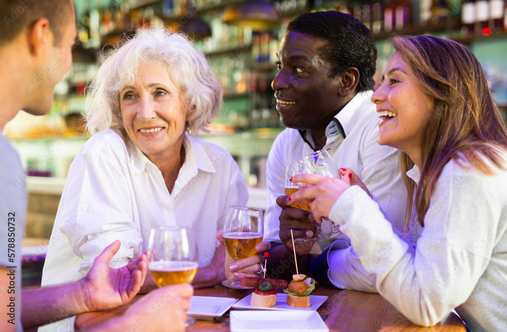 Diverse friends talking and smiling at a pub and drink beer