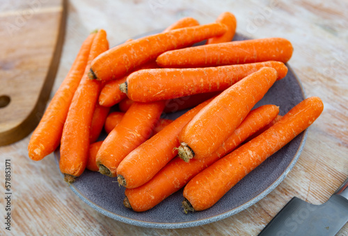 Raw unpeeled carrots on wooden kitchen table, cooking ingredients