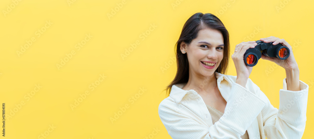 Beautiful caucasian white young woman looking through the twin lens binocular. Woman using binocular portrait on yellow background. Beautiful caucasian white young woman looking through the twin lens binocular. Woman using binocular portrait on yellow background.
