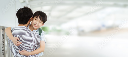 Happy cheerful Asian little boy running to his father at the railway or sky train station after his father returned from the traveling trip. Happy Asian family father and son concept.