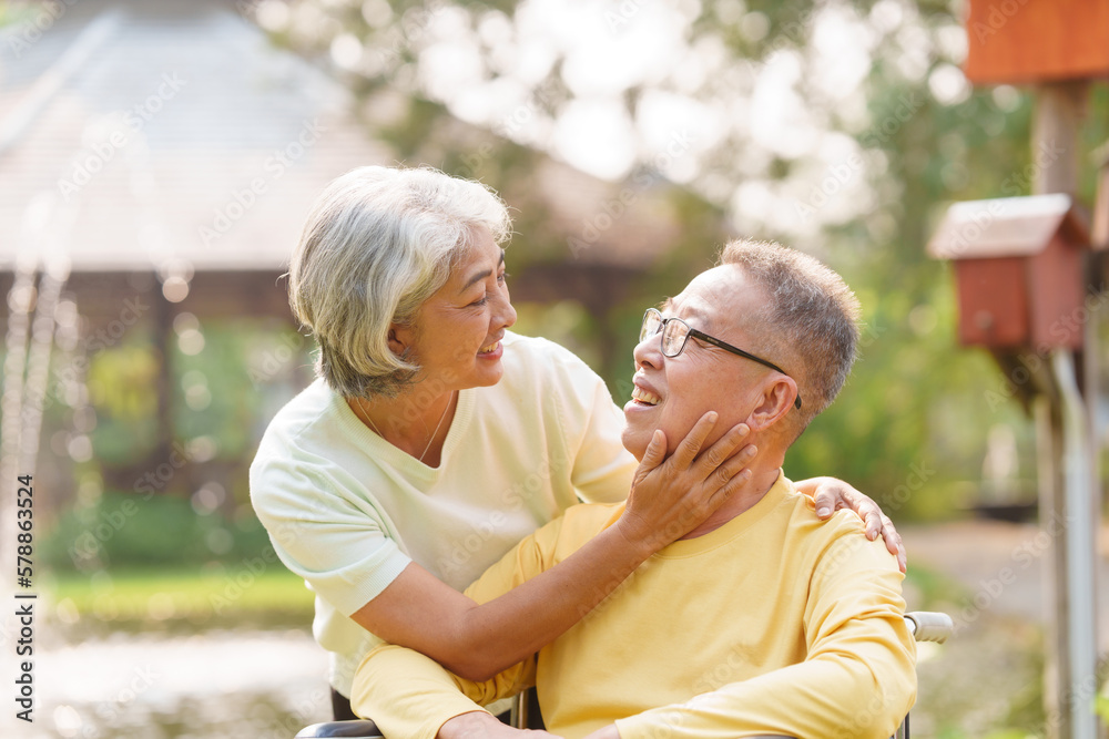 Elderly couple husband and wife happy asian people giving love and care Wheelchair in the park relaxing in spring, relaxing and walking outside at the park.