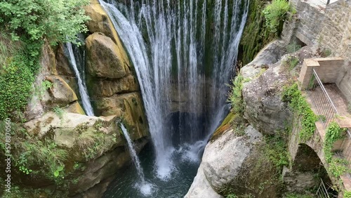 Captivating view at Cascata Arena Uscerno in Roccafluvione (Ascoli Piceno), high-rise waterfall with fresh and pristine waters coming down in copious amounts amongst fiery stones, rocks and vegetation