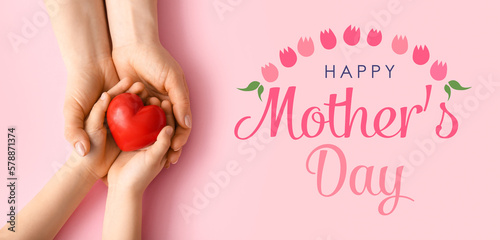 Hands of woman and child with red heart on pink background. Greeting card for Mother's Day
