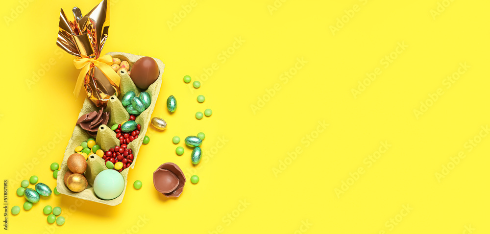 Chocolate Easter eggs and candies on yellow background with space for text Chocolate Easter eggs and candies on yellow background with space for text