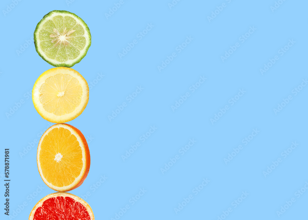 Stack of different fresh citrus fruits on light blue background, space for text Stack of different fresh citrus fruits on light blue background, space for text