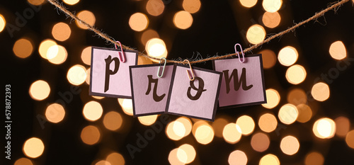 Rope with clips and paper word PROM against blurred lights