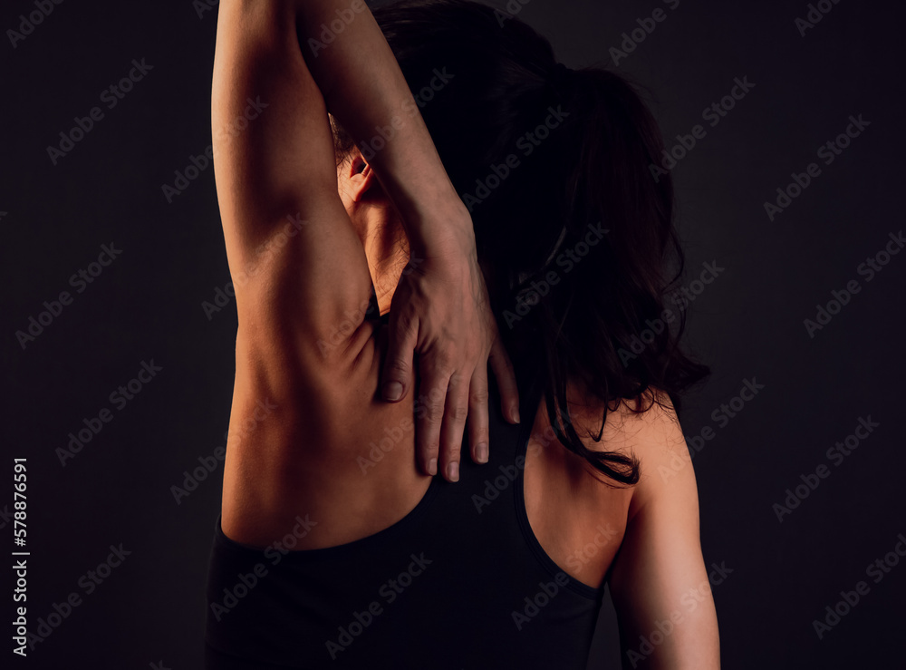 Woman in sport clothing holding the hand the back. Toned color vintage portait