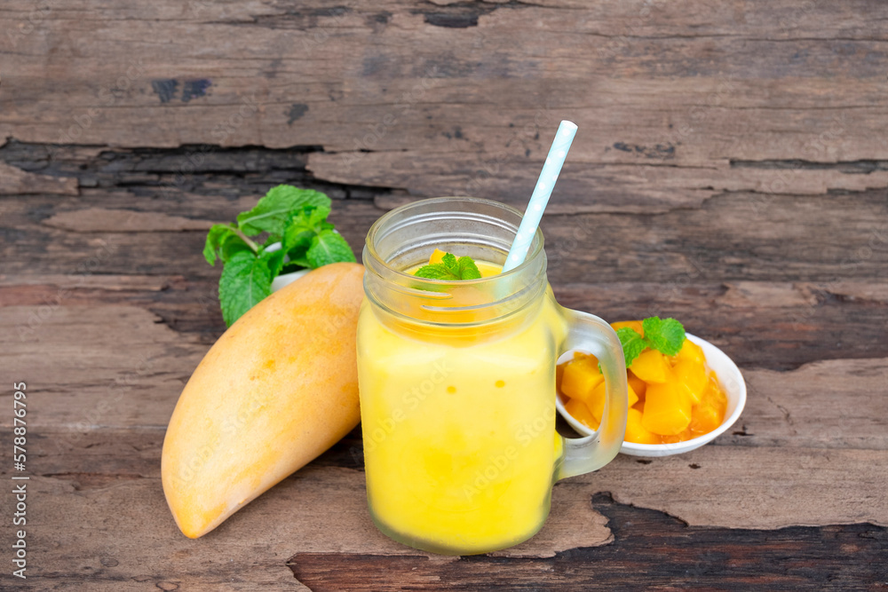 Fototapeta premium Mango juice fruit smoothies yogurt drink yellow healthy delicious taste in a glass slush for weight loss on wooden background.