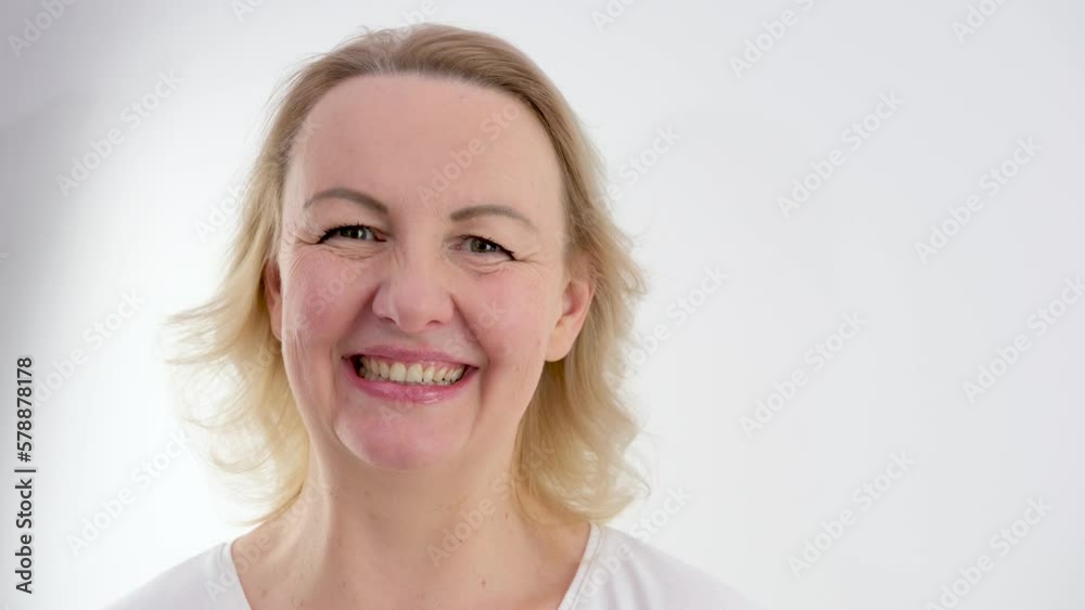 face of middle-aged woman with blond hair on a white background close-up she lowered her eyes sincerely smiles embossed doubt joy tenderness beauty calmness peace face of middle-aged woman with blond hair on a white background close-up she lowered her eyes sincerely smiles embossed doubt joy tenderness beauty calmness peace