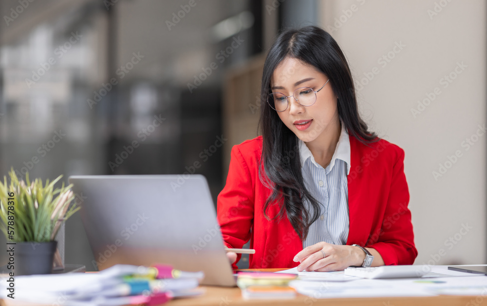 Asian businesswoman analyzing reports while working in workplace office. Asian businesswoman analyzing reports while working in workplace office.