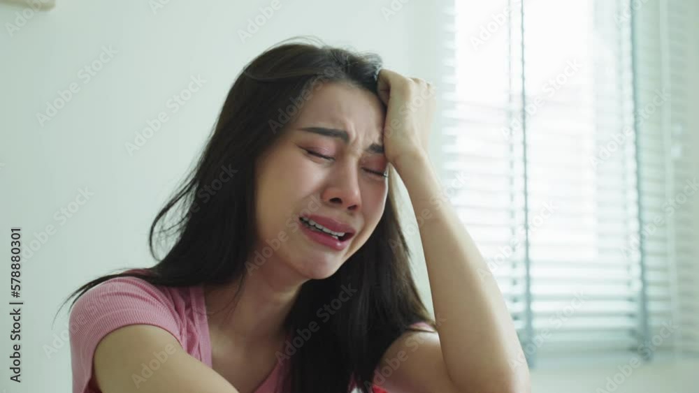 Asian beautiful woman feel angry while sitting alone on bed in bedroom Asian beautiful woman feel angry while sitting alone on bed in bedroom