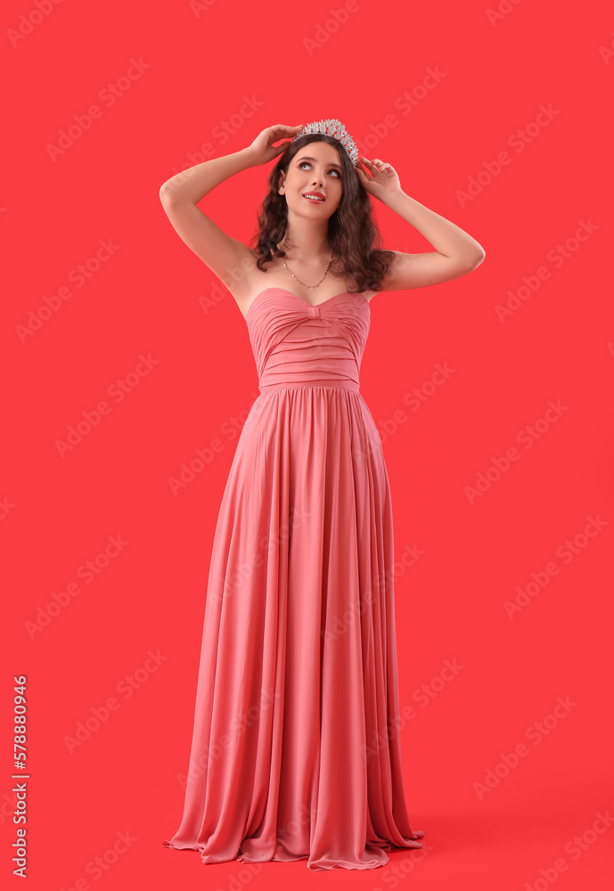 Teenage girl in tiara and prom dress on red background Teenage girl in tiara and prom dress on red background