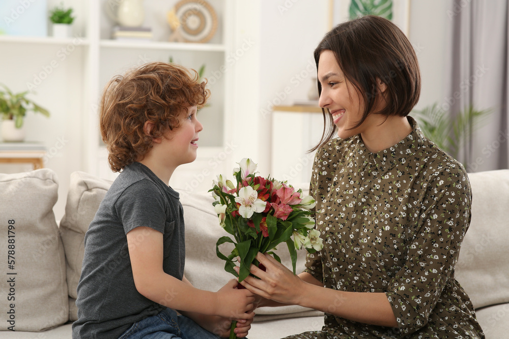 Happy woman with her cute son and bouquet of beautiful flowers at home. Mother's day celebration Happy woman with her cute son and bouquet of beautiful flowers at home. Mother's day celebration
