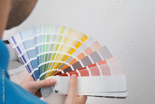 Man with palette choosing color for painting wall indoors, closeup. Interior design © New Africa