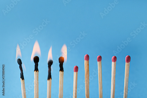 Burning and whole matches on light blue background, closeup. Stop destruction by breaking chain reaction concept