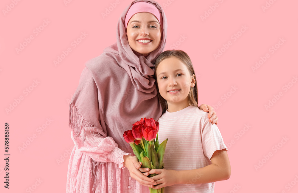 Little girl with tulips and her Muslim mother on pink background Little girl with tulips and her Muslim mother on pink background