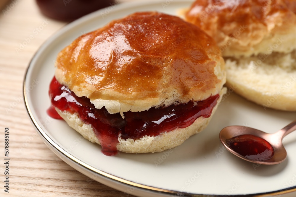 Freshly baked soda water scones with cranberry jam on wooden table, closeup