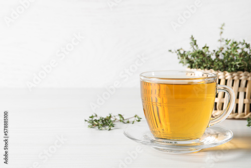 Aromatic herbal tea with thyme on white wooden table, space for text