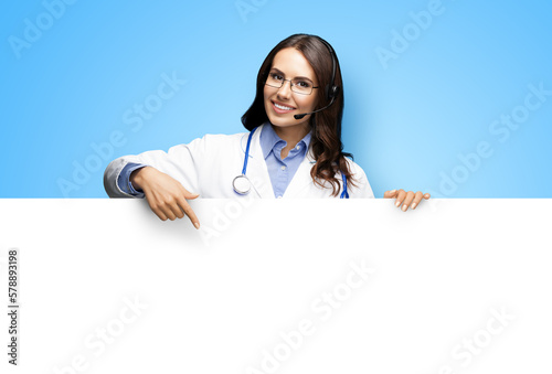 Medical Help Call Center. Smiling doctor in headset. Woman in eye glasses peep behind show white empty signboard banner isolate sky blue background. Online video conference lab pharmacist. Advise
