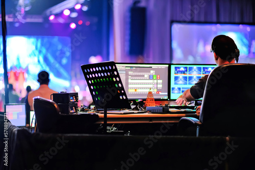 Fotografiet Professional backstage sound engineer operating production live stage audio video mixer, computer monitor to switch scenes, music, sound, lighting effects in holiday show event on blurred background