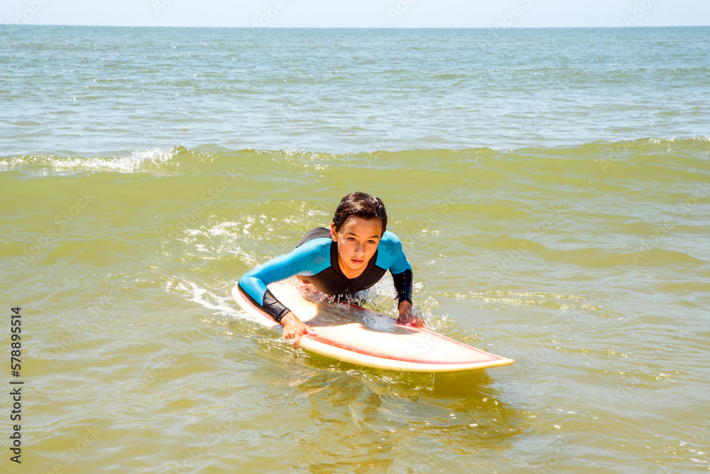 Male teen surfer in action catching a wave on his surfboard Male teen surfer in action catching a wave on his surfboard