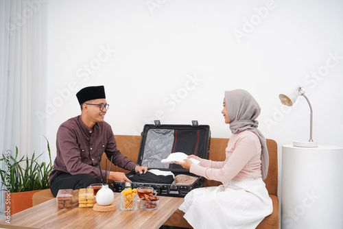 Portrait of Muslim couple preparing suitcase for back to hometown (mudik) before Idul FitriEid al-Fitr at home