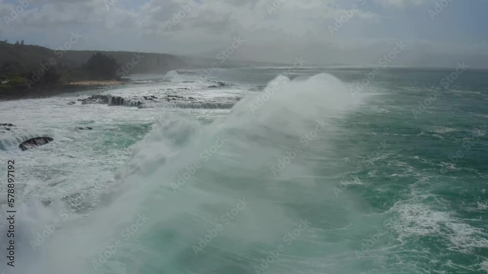 Aerial view of the massive waves of the pacific ocean breaking against the coral rocks and splashing high up into the air of the north shore near sharks cove Hawaii Aerial view of the massive waves of the pacific ocean breaking against the coral rocks and splashing high up into the air of the north shore near sharks cove Hawaii