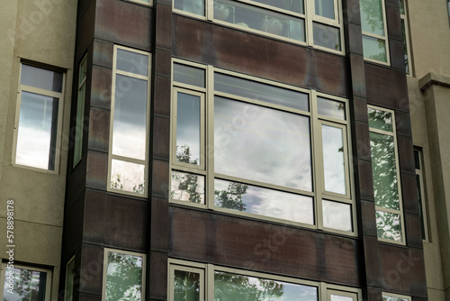 Building facade visible reflective windows and brown stucco with dark accent paint on exterior of apartment building