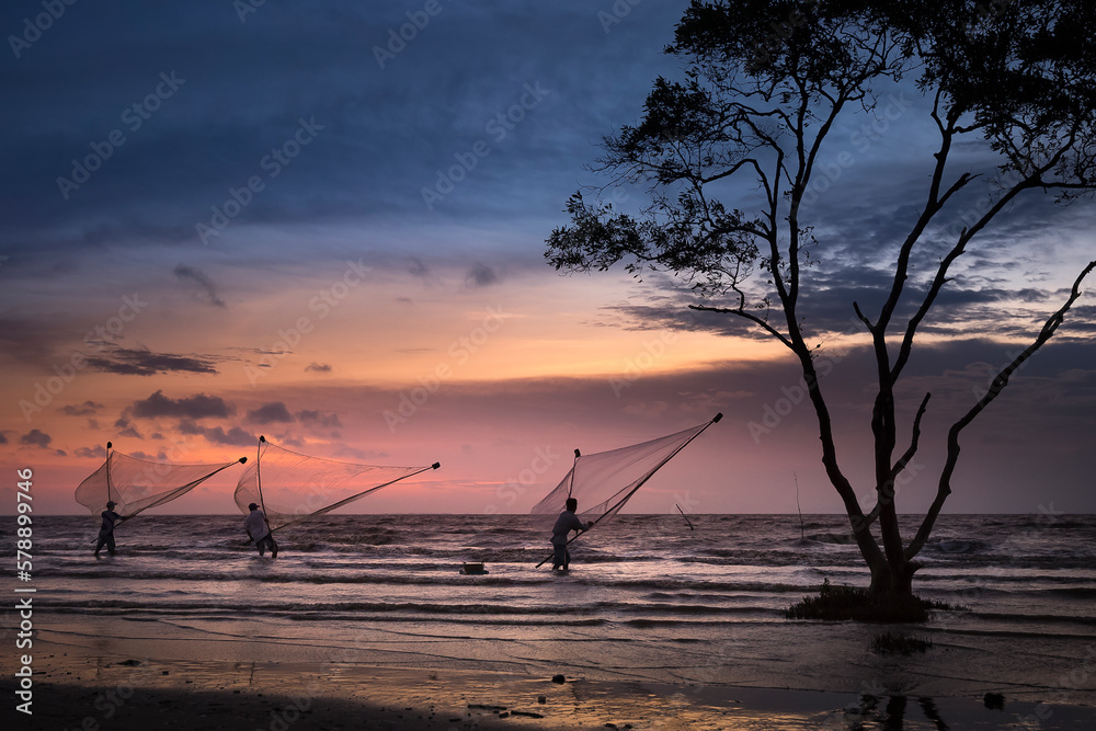 Image of fishing village people using homemade tools to catch fish in sea at sunrise