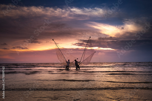 Image of fishing village people using homemade tools to catch fish in sea at sunrise