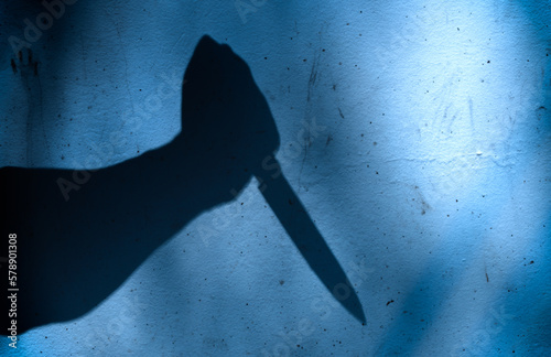 silhouette of hand holding a  knife on wall in crime scene. Dark theme crime scene concept. photo