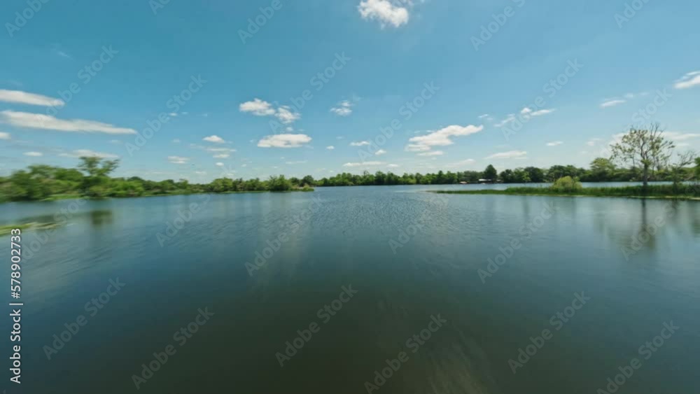 FPV drone cinematic aerial flyover tour of serene colorful Texas lake surrounded by greenery on clear sunny day FPV drone cinematic aerial flyover tour of serene colorful Texas lake surrounded by greenery on clear sunny day