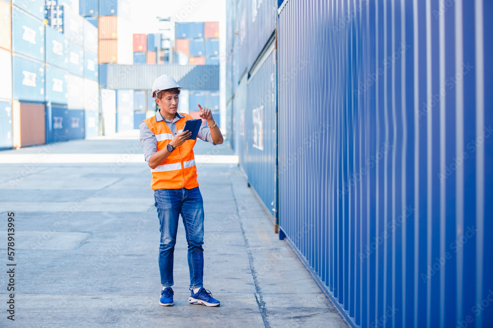Obraz premium Foreman in uniform wearing safety helmet using tablet checking containers loading. Area logistics import export and shipping cargo freight ship.